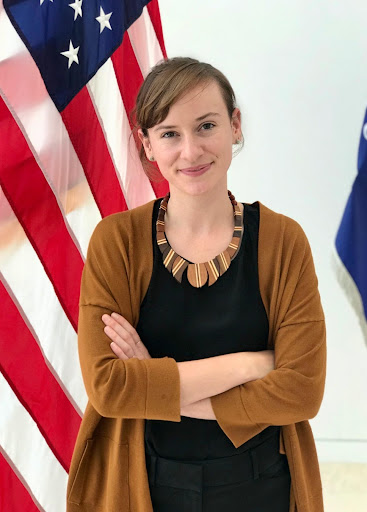 Holland Gormley, public affairs specialist with Copyright Office, standing with her arms crossed next to the American flag.
